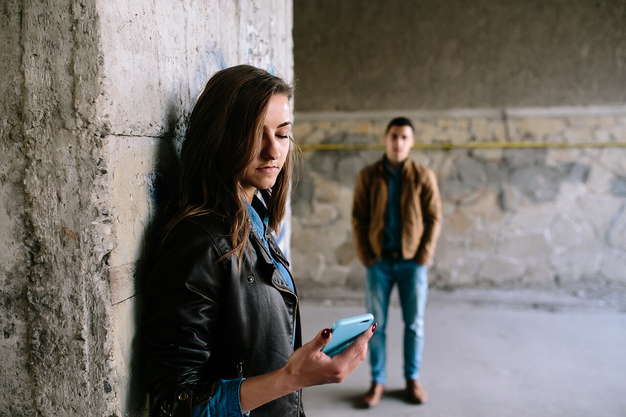 Woman in street holding a mobile phone with a man standing behind her